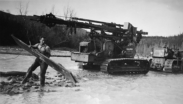 A self-propelled churn drill for finding gold is accompanied across Coal Creek by a Caterpillar tractor crew, ca. 1938. University of Alaska Fairbanks, Stanton Patty Family Papers (2012-93-128)