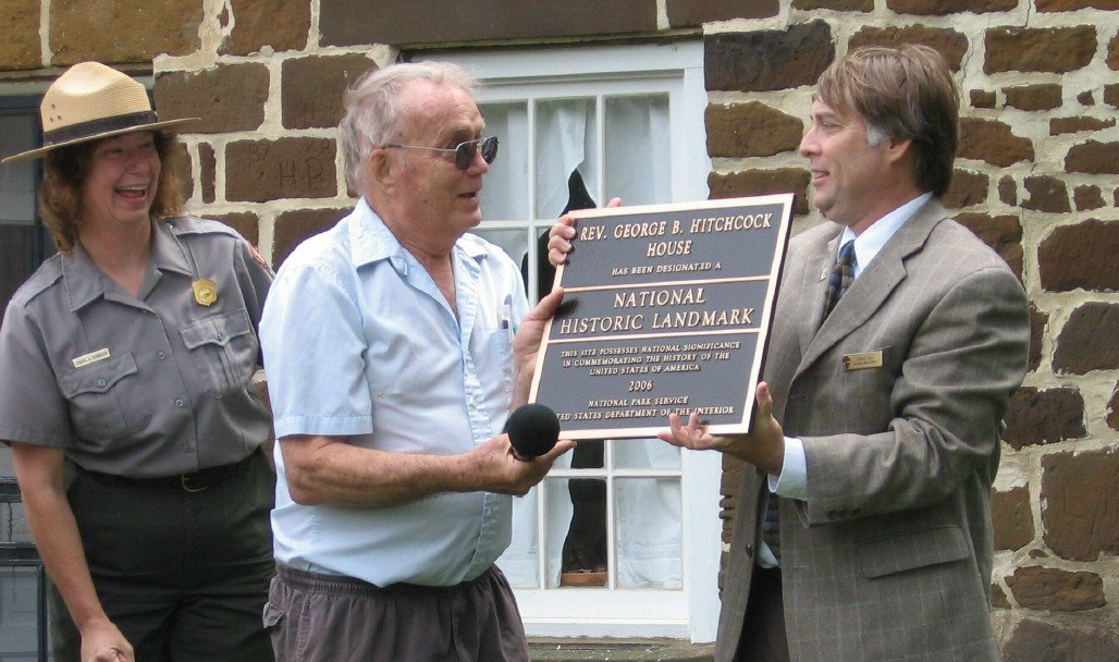 Hitchcock House Designation Three people smiling and holding onto a plaque.