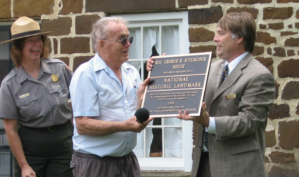 Three people smiling and holding onto a plaque.