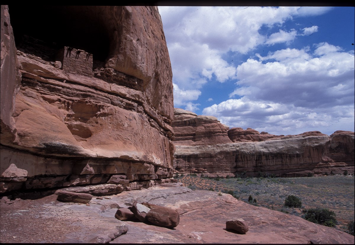 a cliff dwelling in a red rock pocket above a valley