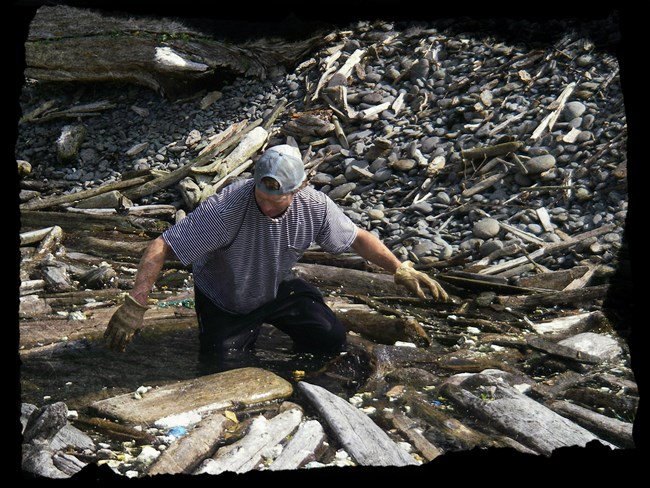 A member of the cleanup crew wades into the water to retrieve trash.