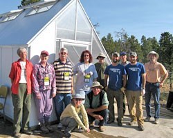 Group of about ten volunteers smiling in front of the greenhouse.