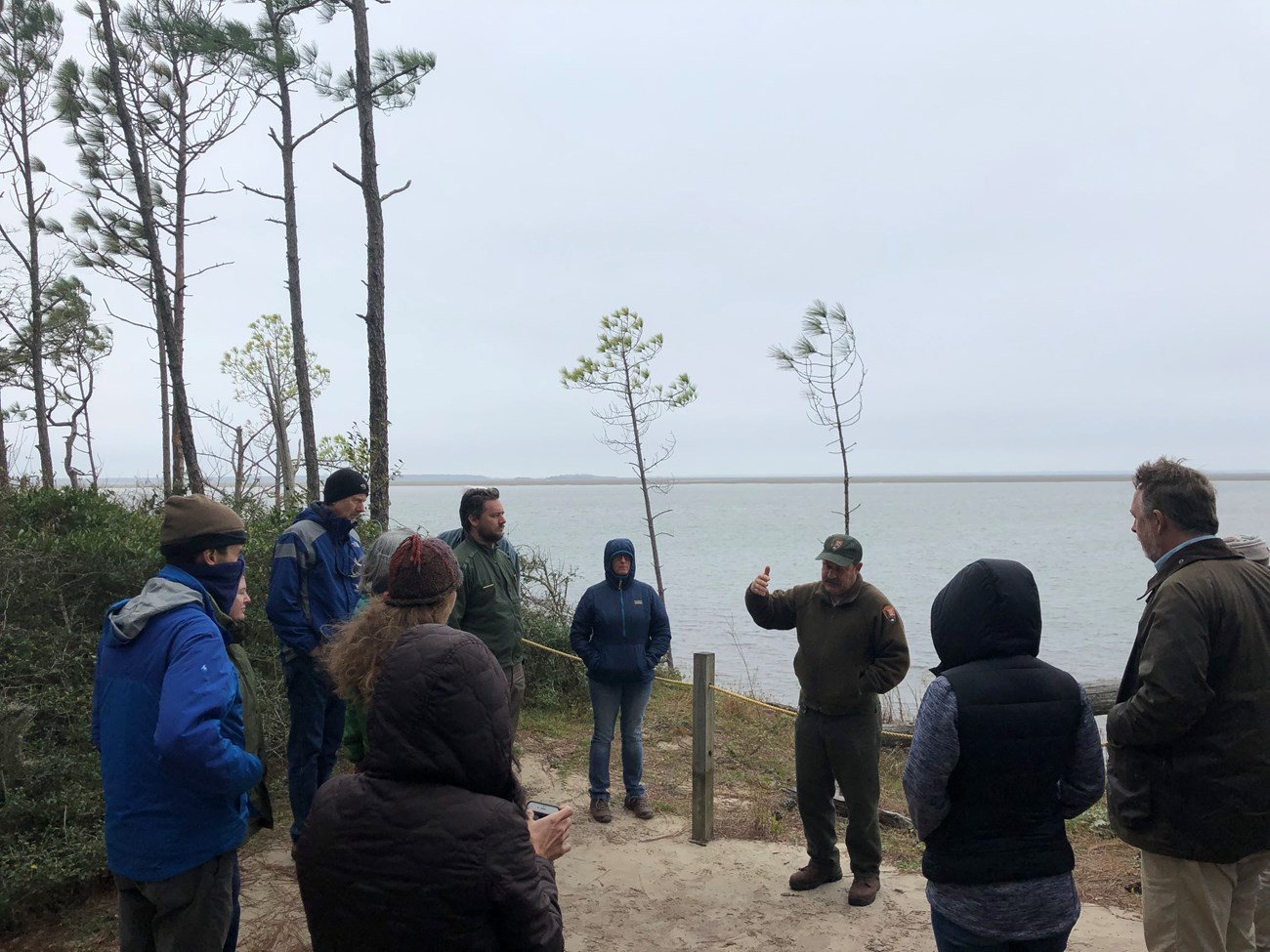 Tour of CUIS People listen to a man talk standing by the water