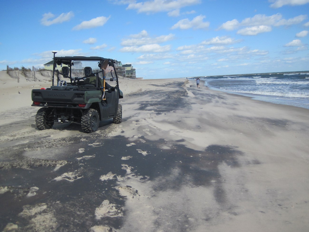UTV rides along the beach with the ocean to the right.