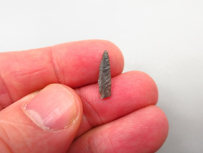 A hand holding a small arrow head