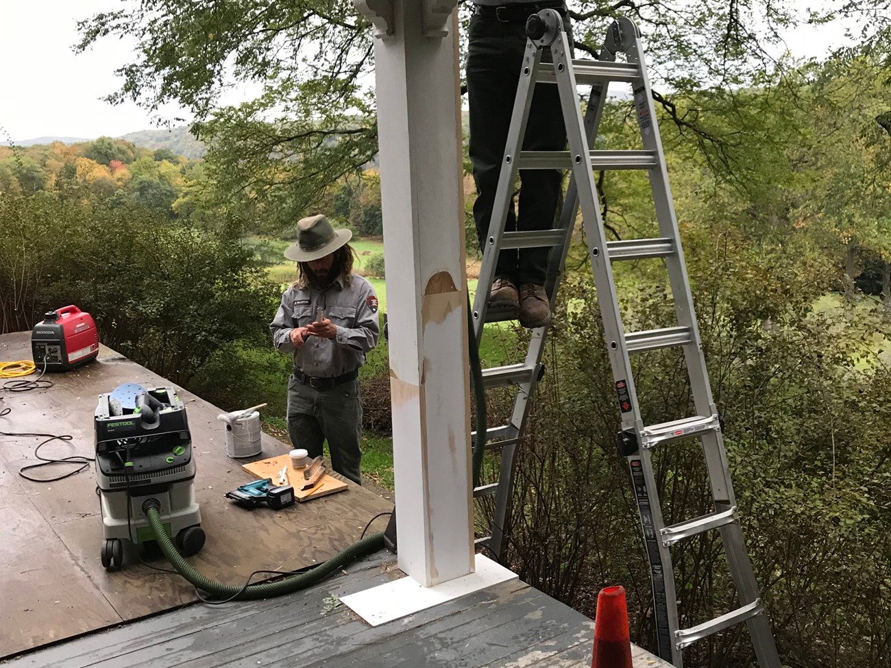 Two Park Rangers repairing a wooden porch.