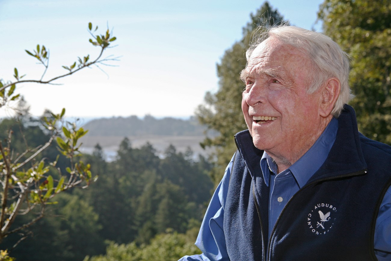 Portrait of a smiling older man outside in the sun, wearing an Audubon Canyon Ranch vest.
