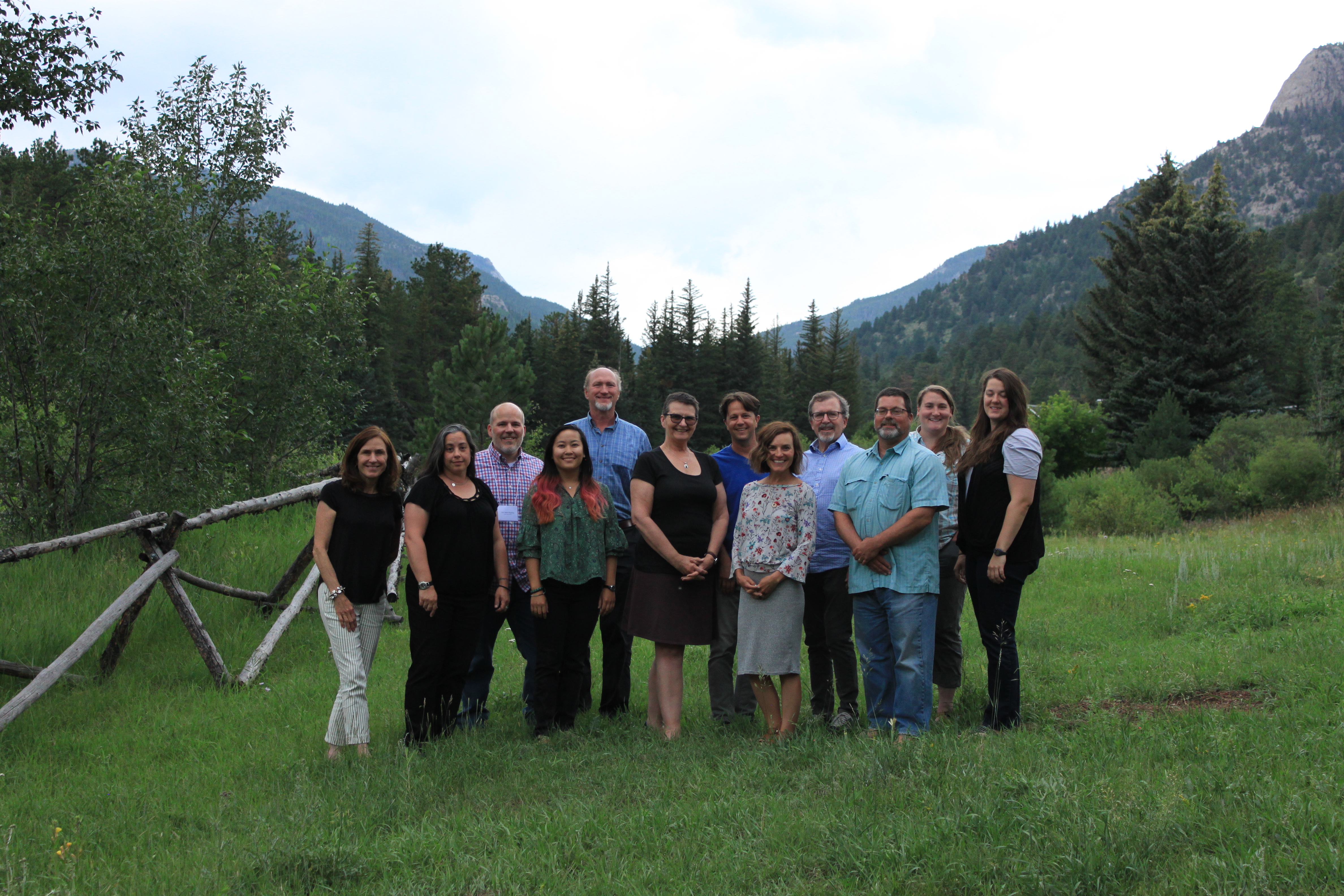 A group of people standing with trees and mountains in the background.