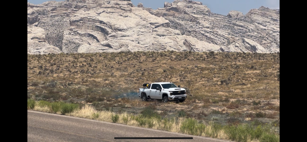 IMPT herbicide application truck spraying herbicide on invasive plants in front of rocky mountain
