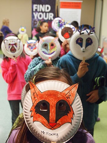 Kids hold up animal masks that they made