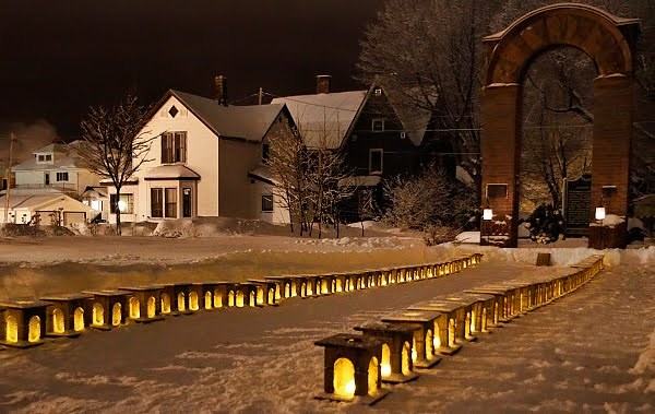 Rows of lit luminaries line a path to the Italian Hall memorial