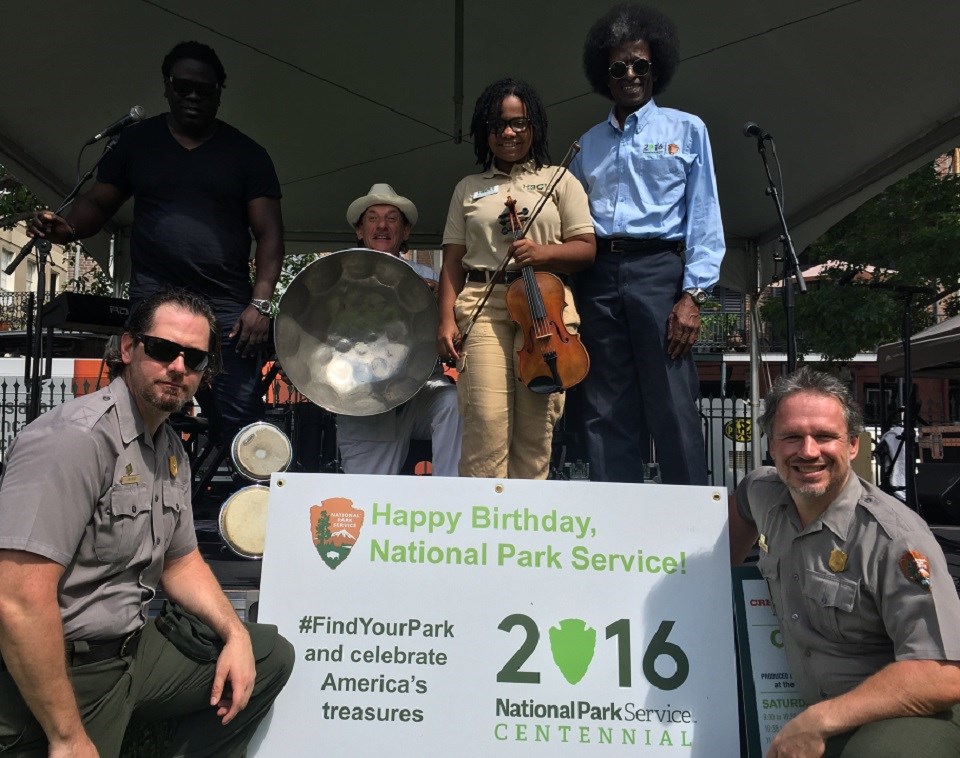 JAZZ Centennial Band Park rangers and volunteers holding instruments and an NPS Centennial sign