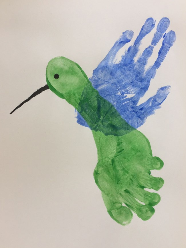 A photo of the complete craft: the body of the bird is a footprint in green paint, the wings a hand print in blue paint