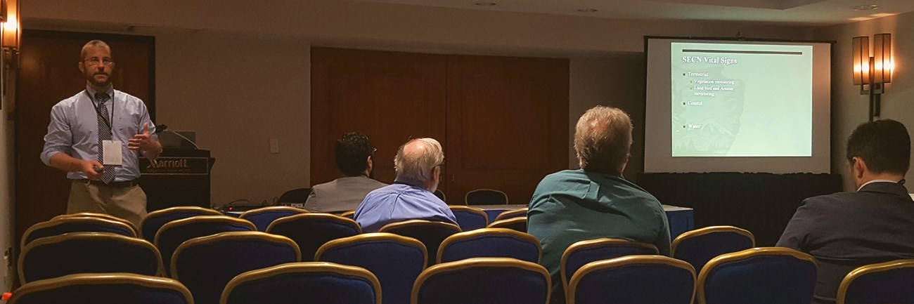 Man standing in front of a room giving a lecture