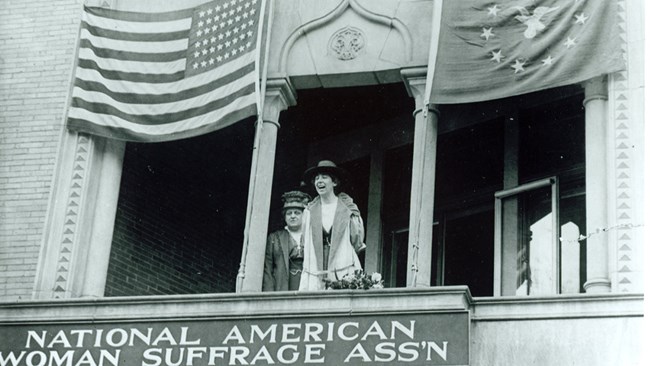 Jeannette Rankin on the balcony of NAWSA headquarters. Carrie Chapman Catt stands beside her