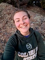 woman poses in front of rocks