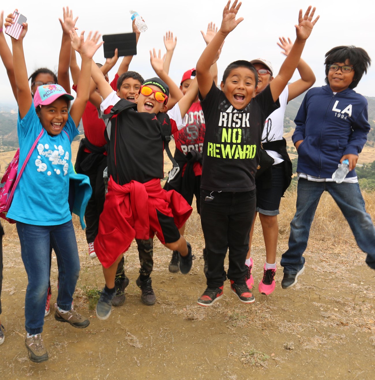 A group of kids on a trail jumping for joy