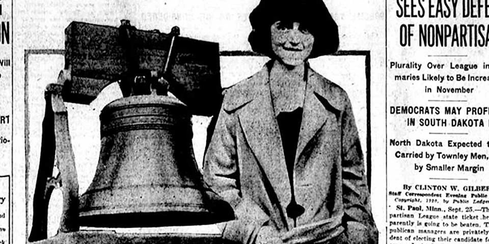 Detail, front page of newspaper showing young woman next to a large bell. Detail, front page of newspaper showing young woman next to a large bell.