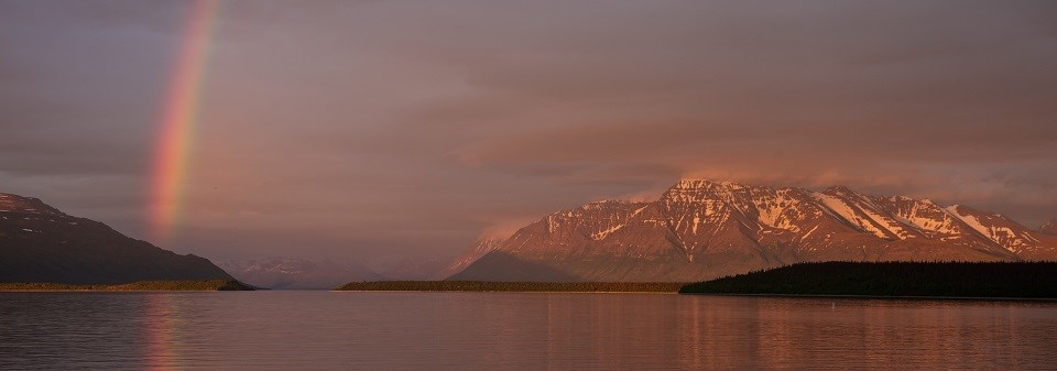 A rainbow appearing over a lake and mountain