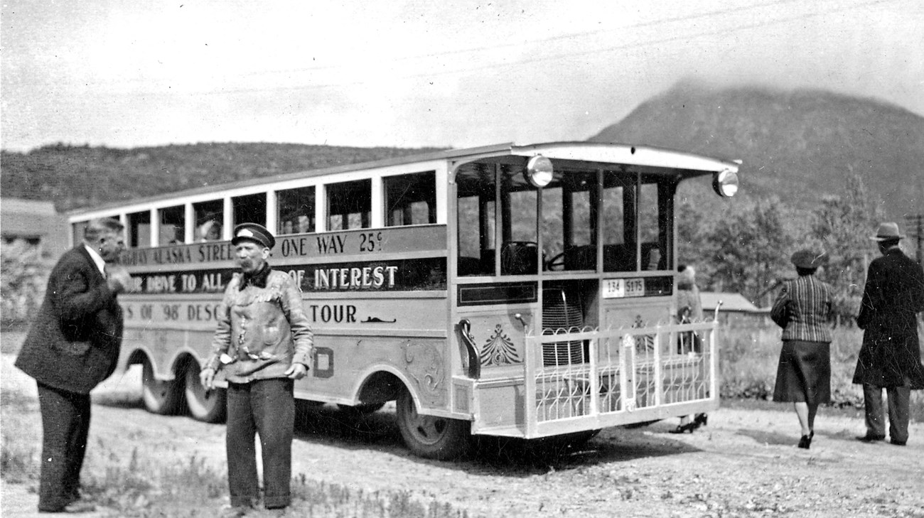 A man standing in front of an old street car made from a train car