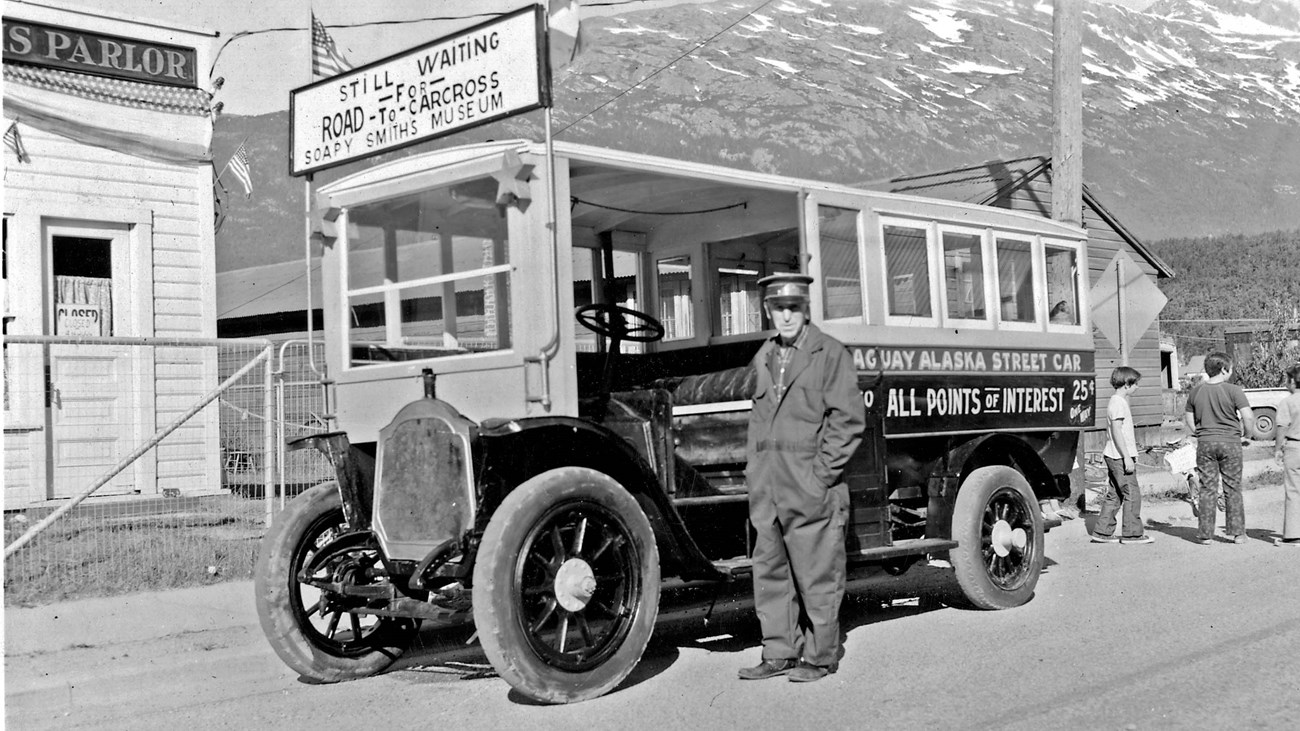 George Rapuzzi stands in front of a street car with a mountain in the background