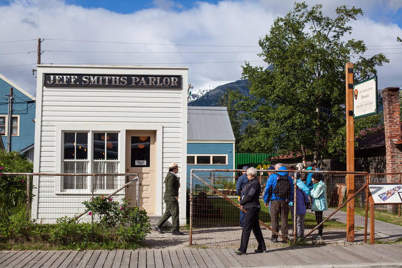 A park ranger and visitors outside of a historic building