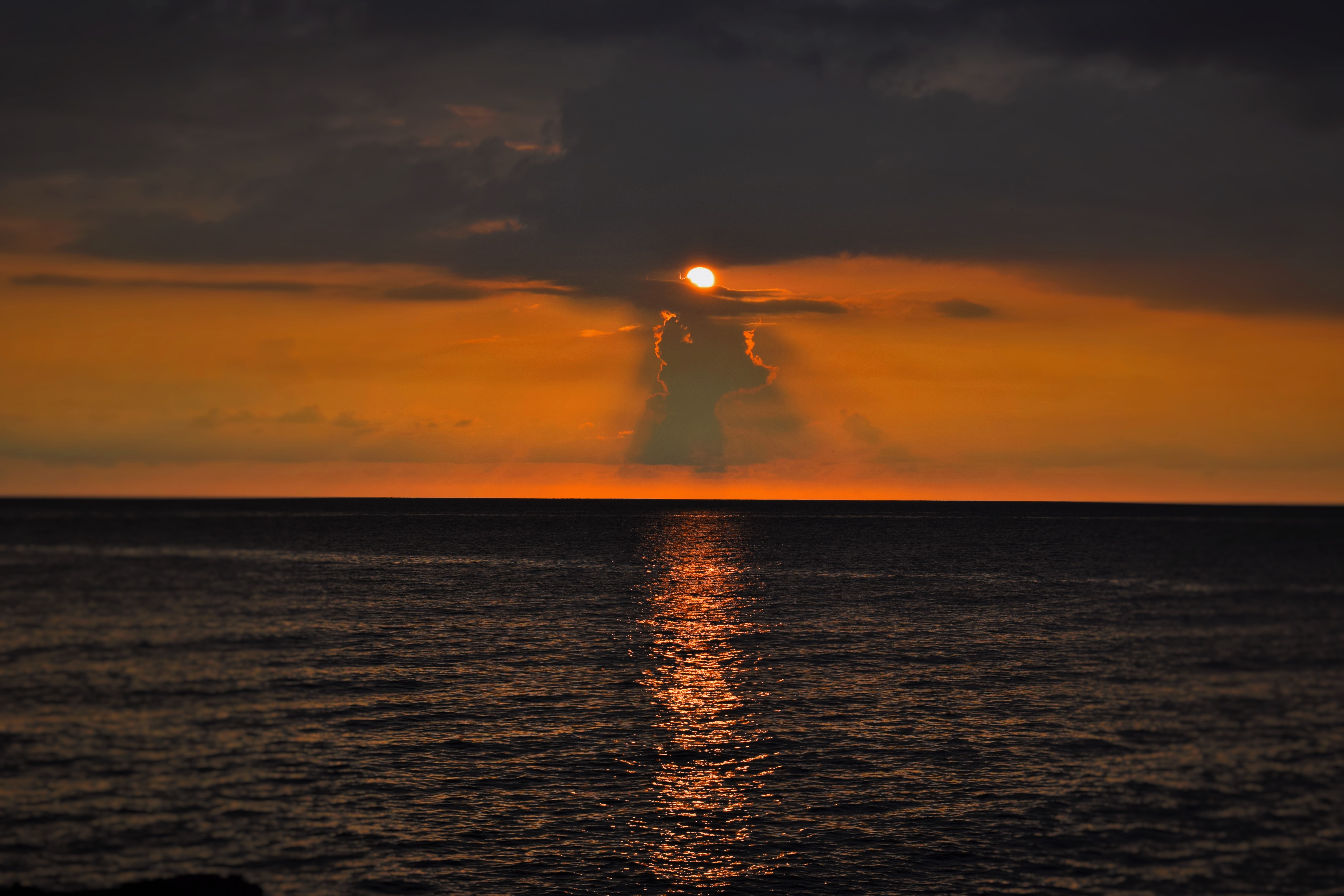 An orange sunset breaking through dark clouds