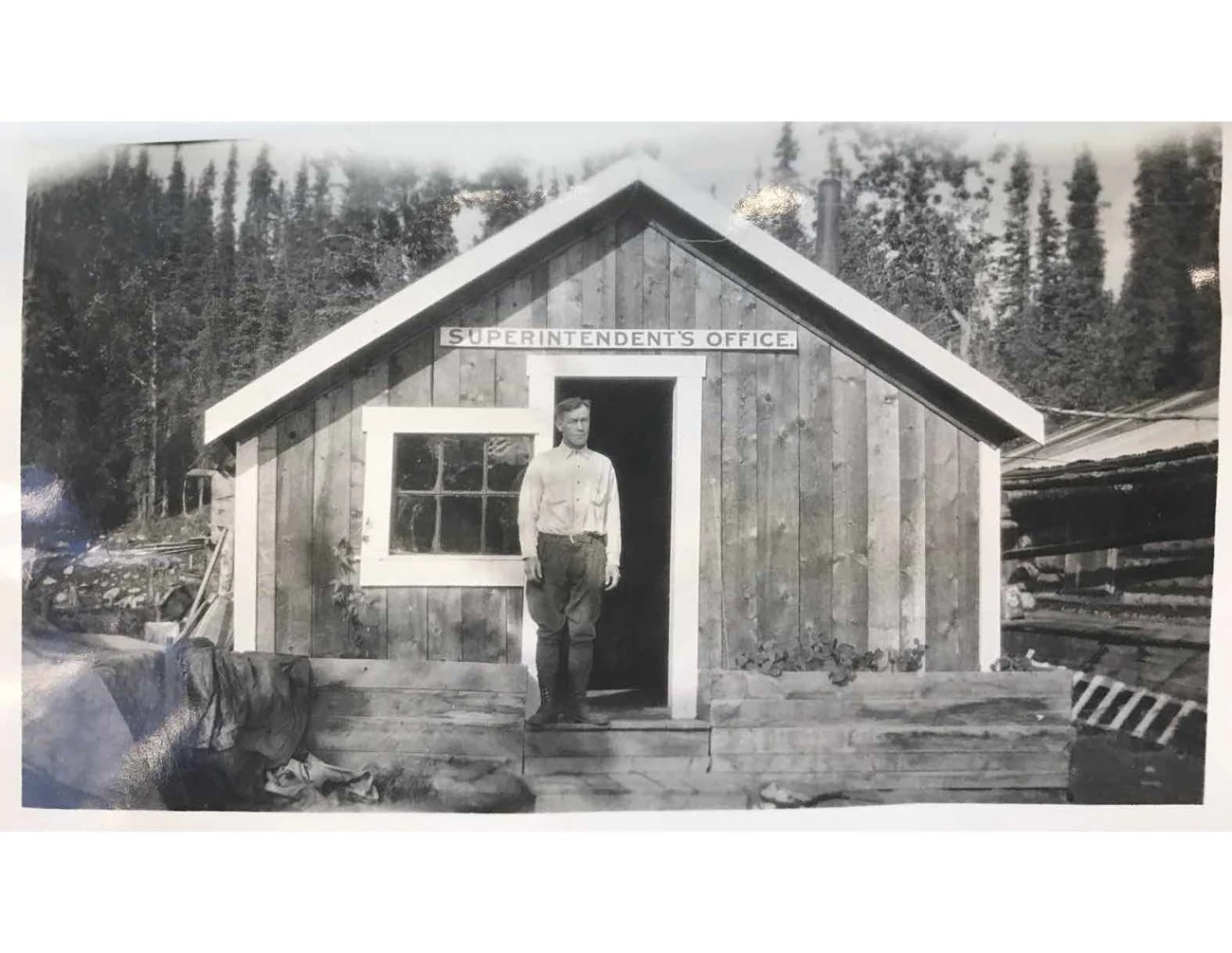 Karstens at original HQ man standing outside a small wooden building in a forest