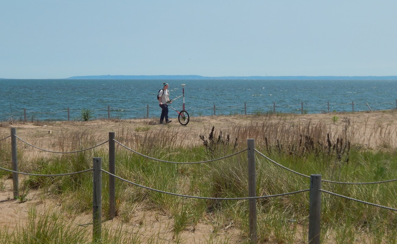lt= Katy ames uses a rover GPS on sand dunes along the coast