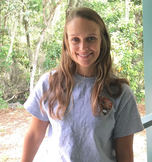 Woman standing on a porch smiling with an NPS t-shirt