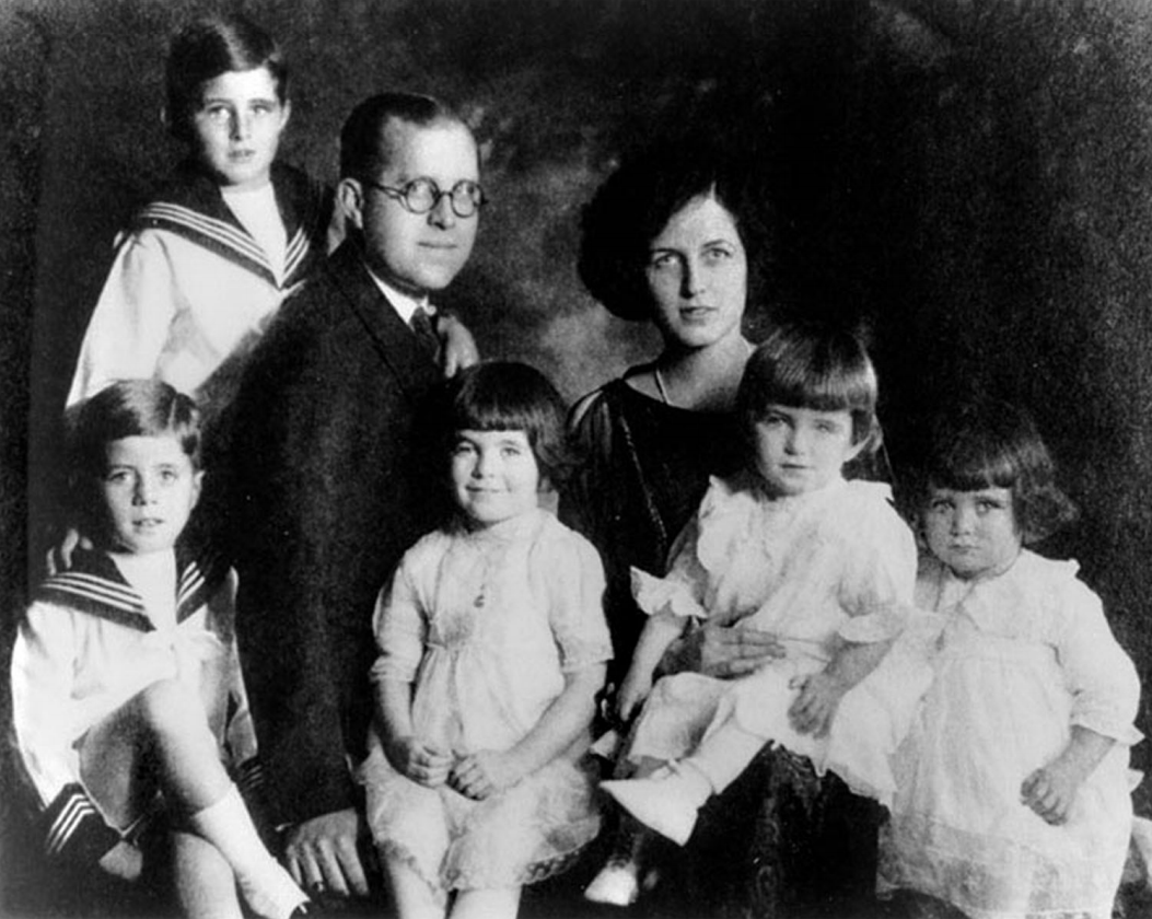 A family posing for a portrait. The children have matching clothing.