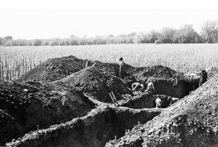 B&W photo of six men digging trenches.