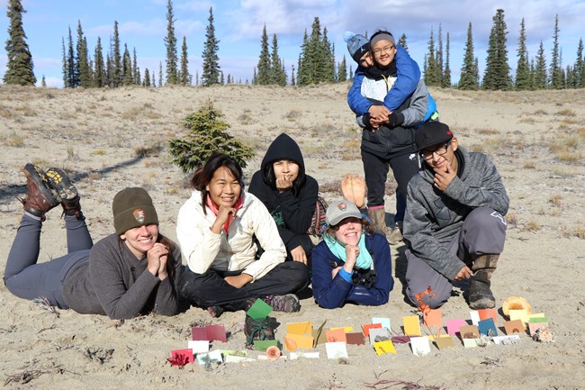 Science Camp for Inupiaq Students at Kobuk youth and a park ranger laying on a sandy hillside