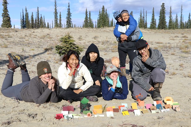 youth and a park ranger laying on a sandy hillside