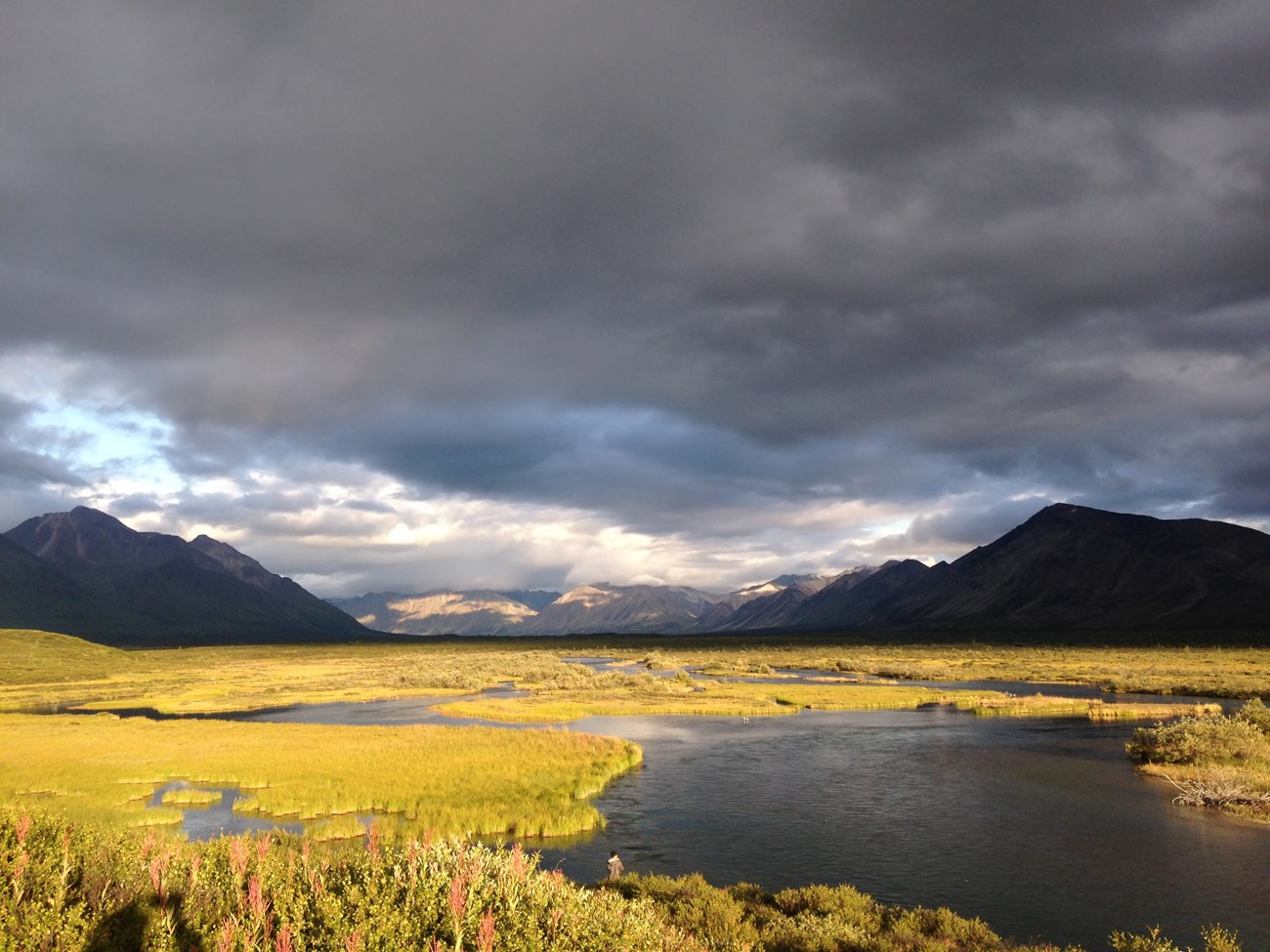 River at sunset with mountains in background.