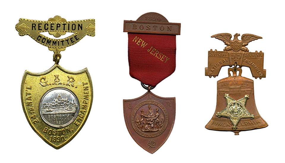 Three medals: gold and silver colored shield-shaped medal, shield-shaped medal on dark red ribbon, medal in shape of bell surmounted by eagle