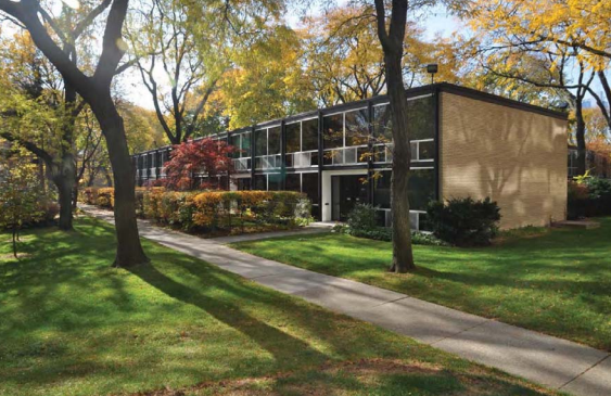 Townhouse units with large windows surrounded by orange and green trees.