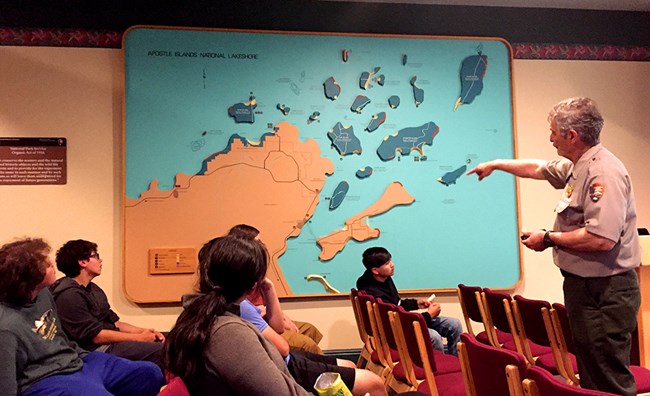 A park ranger points out islands on a map to students. A park ranger points out islands on a map to students.
