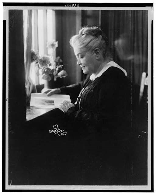 Miss Laura Clay, half-length portrait, seated at desk reading, facing left