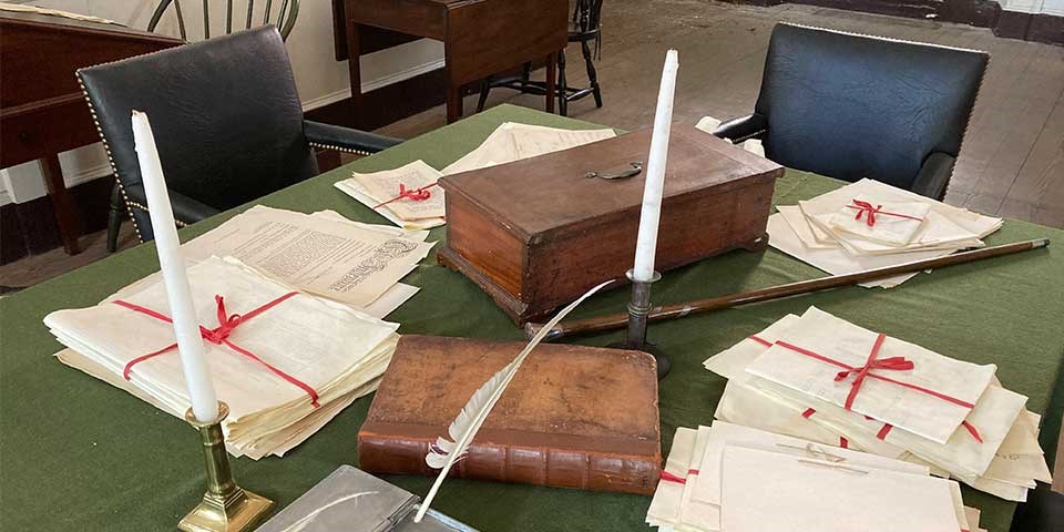 A document box sits on a table surrounded by a book, candlestick and walking stick.