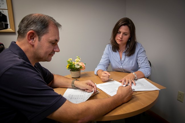 Administration workers meet over papers on a table