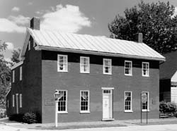 B&W photo of a two-story brick home with many windows.