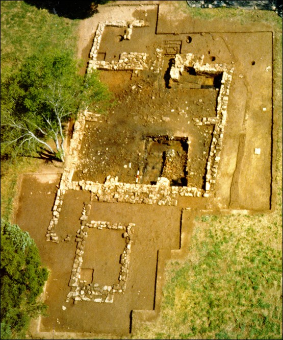 Aerial view shows the stone foundations, excavated domestic servant quarters and surrounding trees.