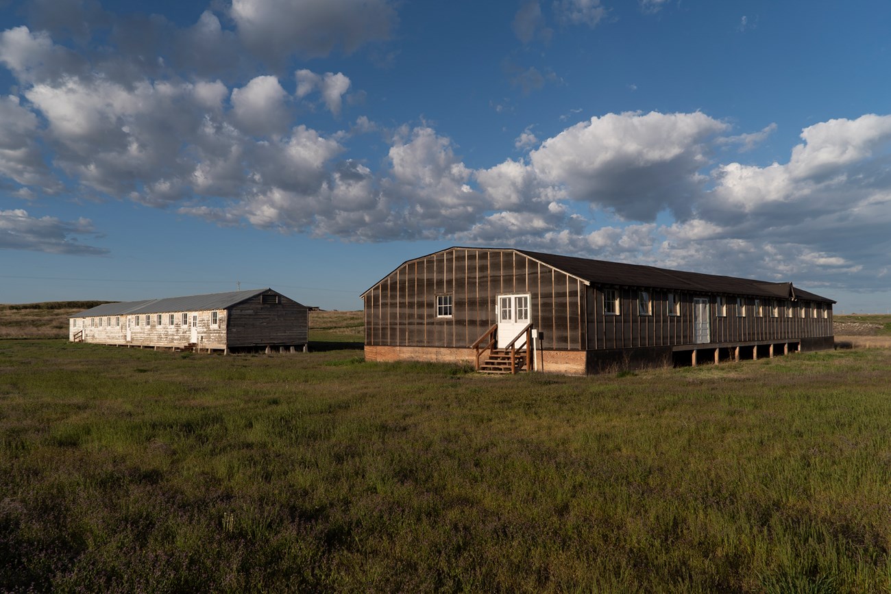 Two long wooden buildings on a grass field