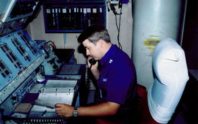 Officer on phone while seathed at desk with buttons