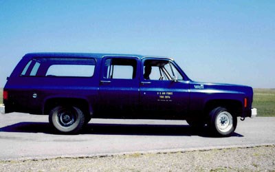 A blue suburban in a prairie landscape