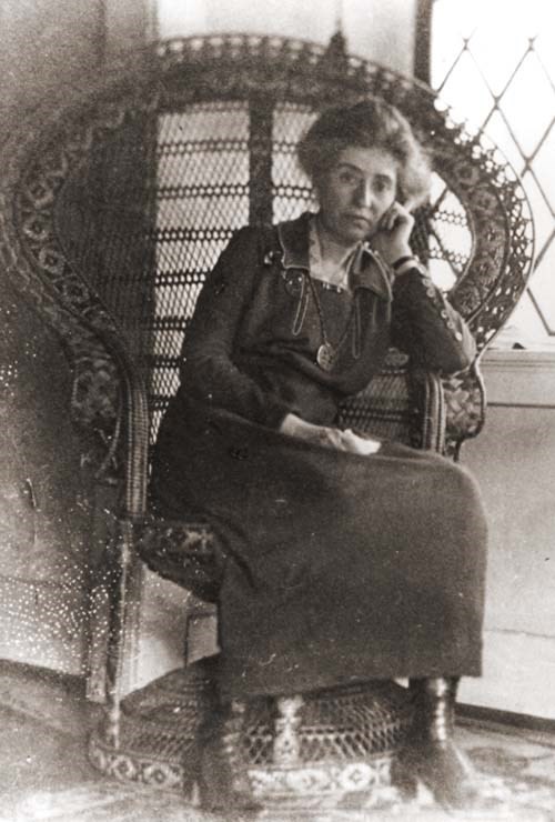 Mary Colter, age 50. Full length photo of Mary Colter sitting in an elaborate wicker chair that wraps around her.
