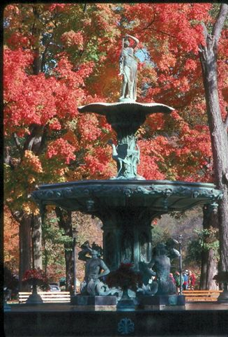 Madison Broadway Fountain Stone fountain among bright red trees.
