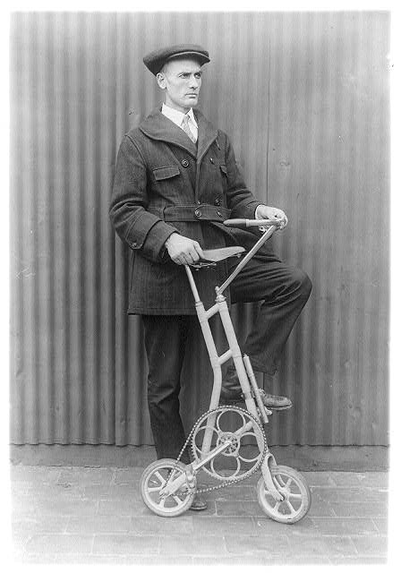 A man standing with a uniquely shaped bicycle.