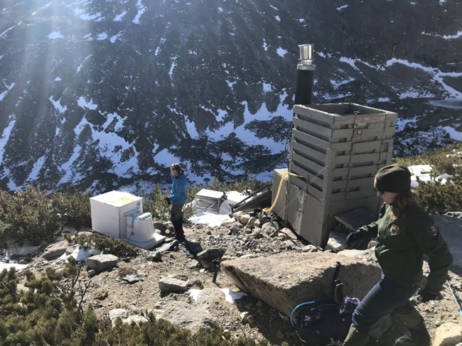 Marina Connors checking out the pilot toilet and existing toilet at Chasm Junction, on the trail to Longs’ Peak. In background, Tara Vessela - Wilderness Ranger.